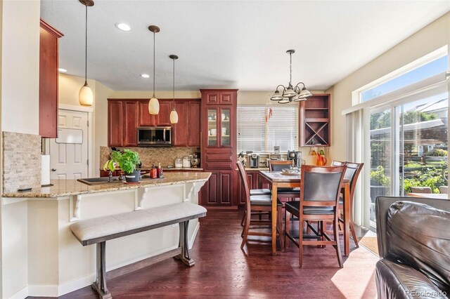 14119 W 89th Loop, Arvada, CO 80005 - kitchen featuring stainless steel microwave, backsplash, a peninsula, pendant lighting, and light stone countertops