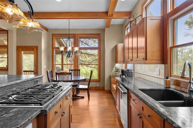 1122 Forest Trails Dr, Castle Pines, CO 80108 - kitchen with stainless steel gas cooktop, light wood-style floors, beam ceiling, dishwasher, and a chandelier
