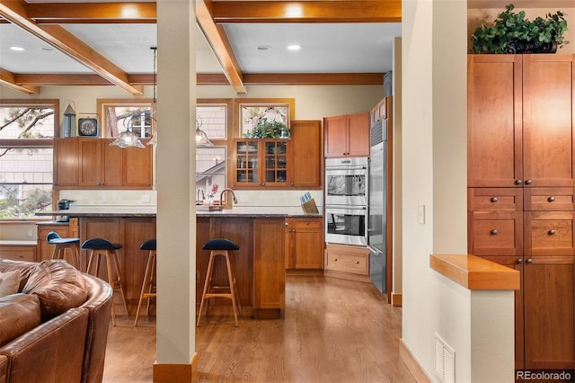1122 Forest Trails Dr, Castle Pines, CO 80108 - kitchen with double oven, light wood finished floors, a breakfast bar, brown cabinetry, and open floor plan