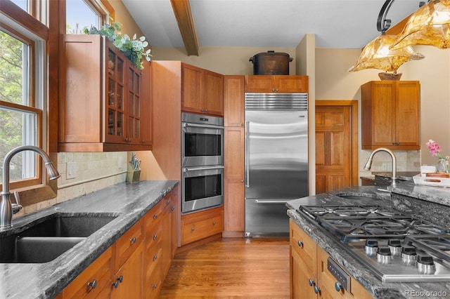 1122 Forest Trails Dr, Castle Pines, CO 80108 - kitchen featuring appliances with stainless steel finishes, beam ceiling, decorative backsplash, and dark stone counters