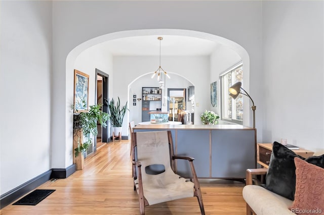 dining room featuring light wood-type flooring, visible vents, a notable chandelier, and baseboards