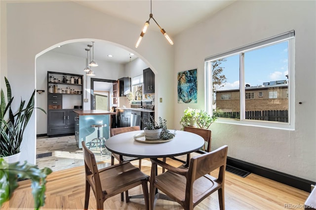 dining space with visible vents, arched walkways, light wood-style flooring, and baseboards