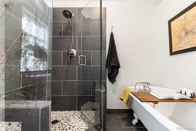 bathroom featuring a soaking tub, a shower stall, baseboards, and tile patterned flooring