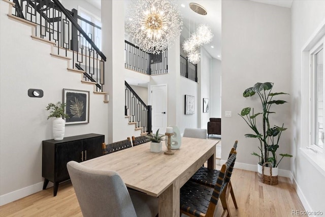4505 S Yosemite St Unit 362, Denver, CO 80237 - dining area featuring stairs, light wood-type flooring, a chandelier, a high ceiling, and baseboards