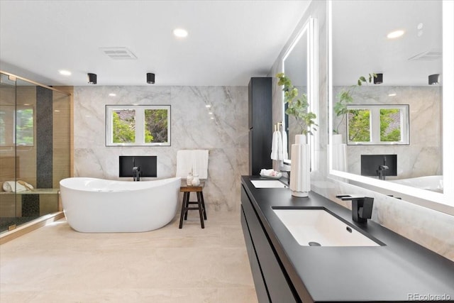 4505 S Yosemite St Unit 362, Denver, CO 80237 - full bathroom featuring tile walls, double vanity, a freestanding bath, a shower stall, and plenty of natural light