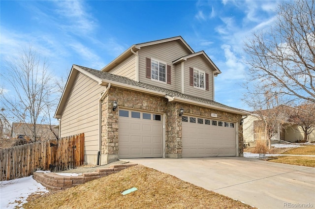 exterior space featuring a garage, stone siding, concrete driveway, and fence