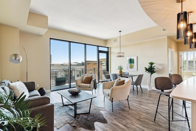 living room featuring plenty of natural light, wood-type flooring, and an inviting chandelier