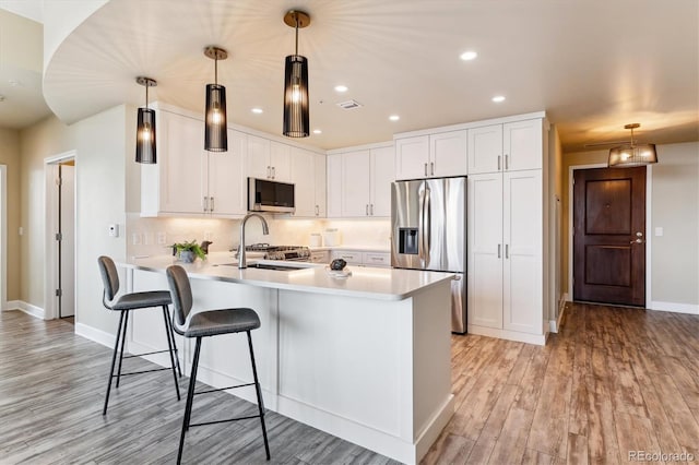 kitchen with appliances with stainless steel finishes, decorative light fixtures, and white cabinetry