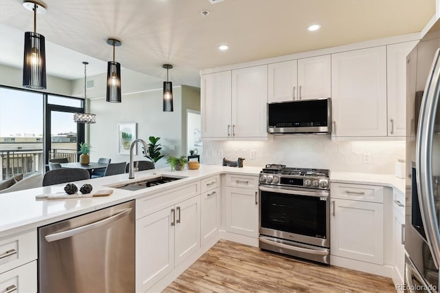 kitchen featuring pendant lighting, sink, white cabinets, backsplash, and stainless steel appliances