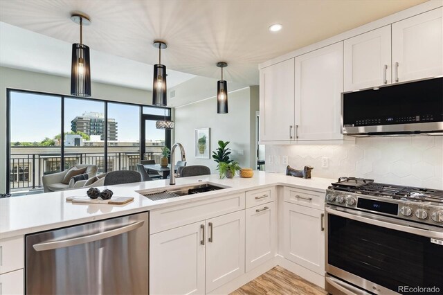 kitchen with white cabinetry, stainless steel appliances, sink, and hanging light fixtures