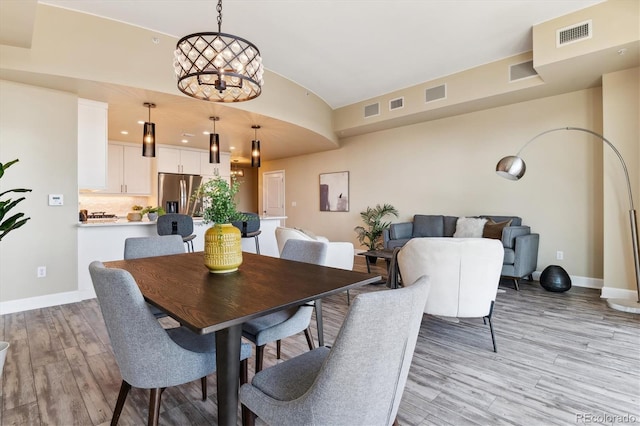 dining room featuring lofted ceiling, a notable chandelier, and light hardwood / wood-style flooring