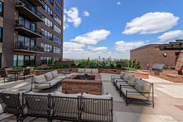 view of patio featuring a grill, exterior kitchen, and an outdoor living space with a fire pit