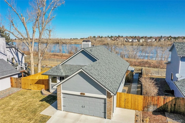 traditional-style home with driveway, a garage, a water view, fence, and brick siding