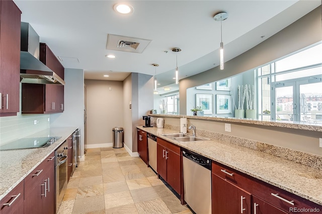 kitchen with appliances with stainless steel finishes, hanging light fixtures, light stone countertops, wall chimney exhaust hood, and sink