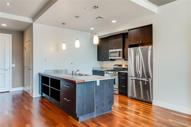 kitchen with stainless steel appliances, sink, decorative light fixtures, hardwood / wood-style flooring, and dark brown cabinetry