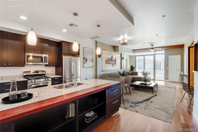 kitchen featuring decorative light fixtures, stainless steel appliances, ceiling fan, and dark brown cabinets