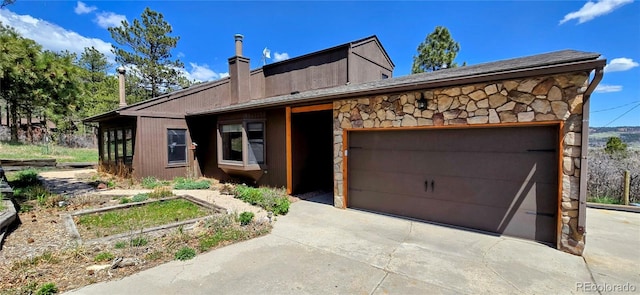 18170 Forest View Rd, Monument, CO 80132 - view of front of house with stone siding, a garage, a chimney, and driveway