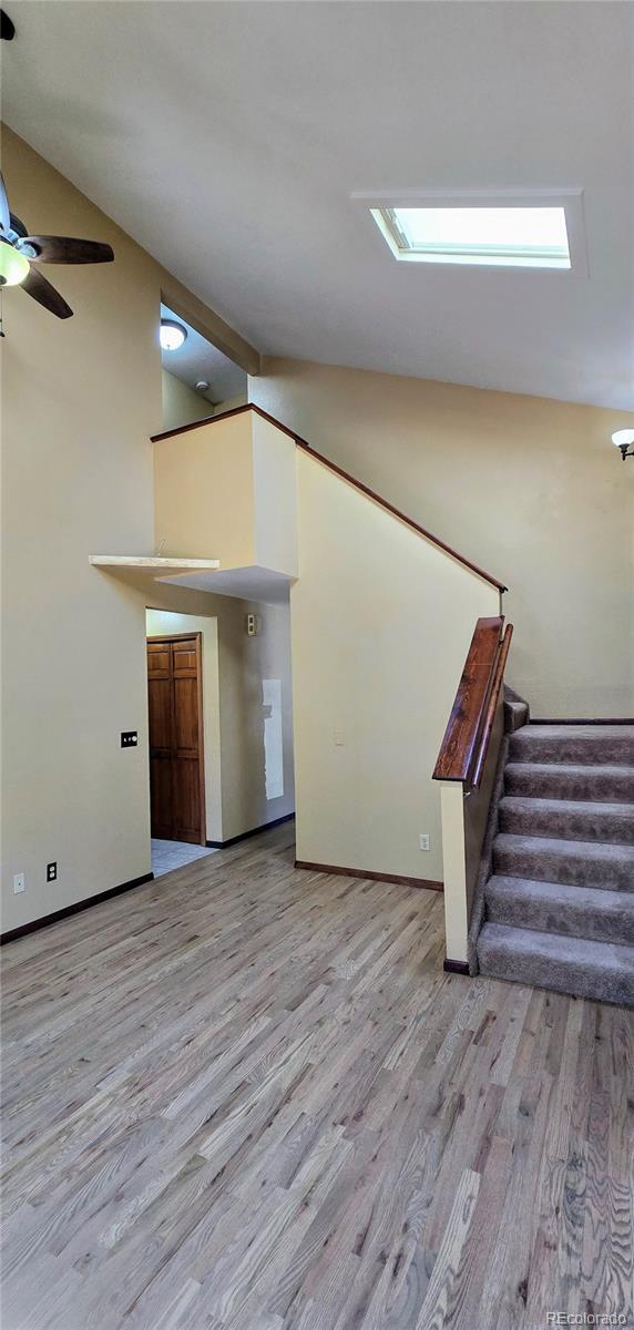 18170 Forest View Rd, Monument, CO 80132 - unfurnished living room featuring light wood-style flooring, stairway, high vaulted ceiling, ceiling fan, and baseboards