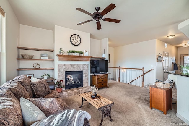 living room featuring carpet flooring, ceiling fan, and a tile fireplace