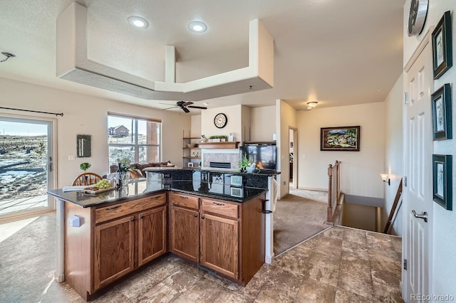 kitchen with ceiling fan, dark stone countertops, carpet floors, a textured ceiling, and a kitchen island