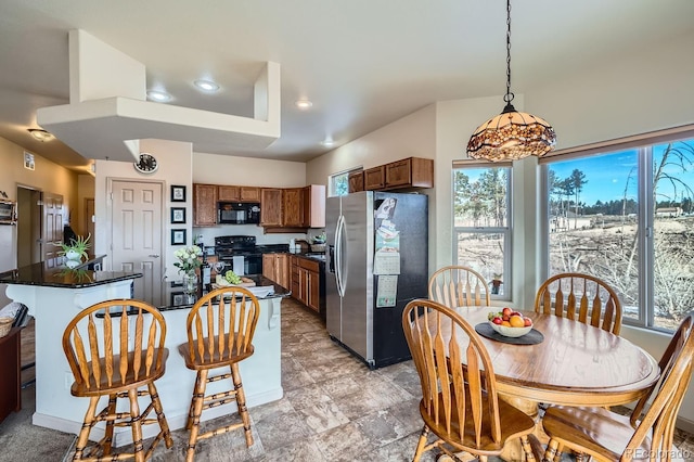 kitchen featuring a center island, hanging light fixtures, a healthy amount of sunlight, and black appliances