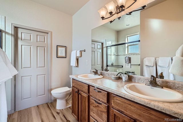 bathroom with wood-type flooring, vanity, toilet, and a shower with door