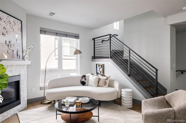 living room with light wood-type flooring and a stone fireplace