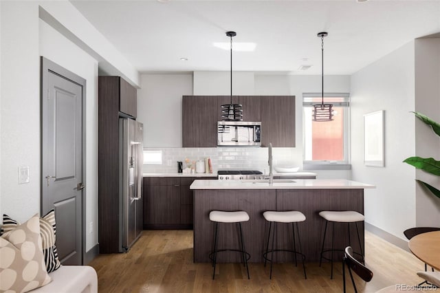 kitchen featuring decorative light fixtures, appliances with stainless steel finishes, and dark brown cabinets