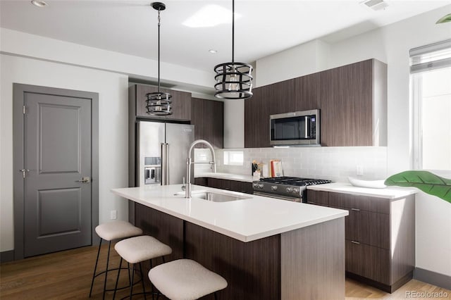 kitchen featuring sink, hanging light fixtures, a kitchen island with sink, and high end appliances