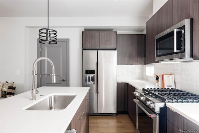 kitchen with tasteful backsplash, pendant lighting, sink, dark brown cabinets, and high quality appliances