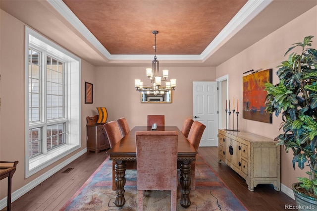 dining room featuring visible vents, baseboards, wood-type flooring, a tray ceiling, and a chandelier