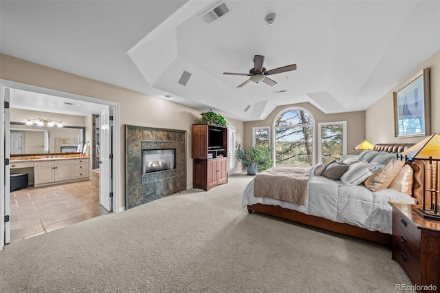 bedroom featuring a fireplace, visible vents, light carpet, connected bathroom, and vaulted ceiling