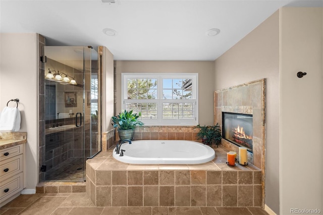 bathroom featuring vanity, a fireplace, a shower stall, and a bath