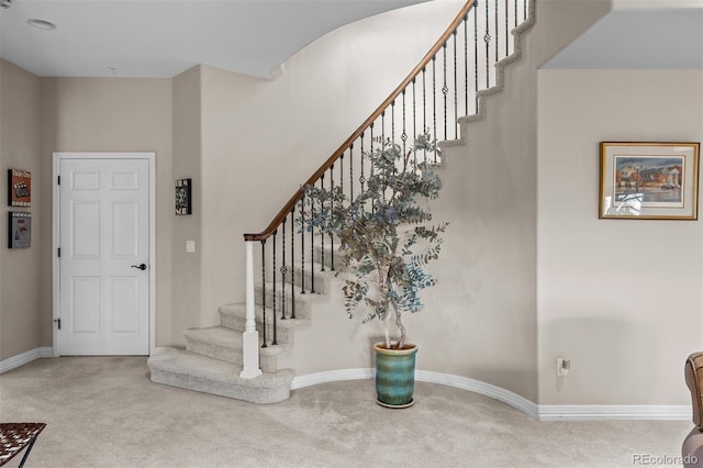 foyer featuring carpet, baseboards, and stairs