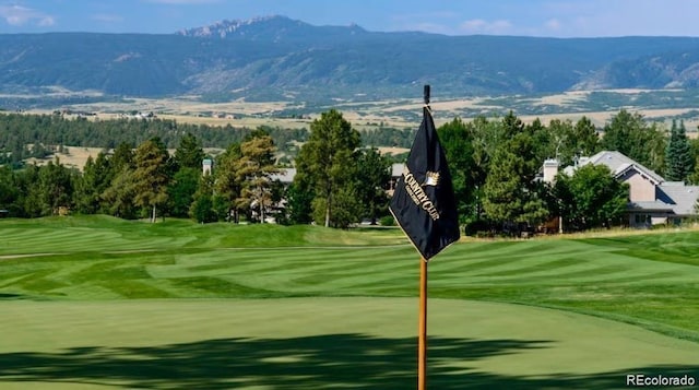 view of community with view of golf course, a mountain view, and a yard