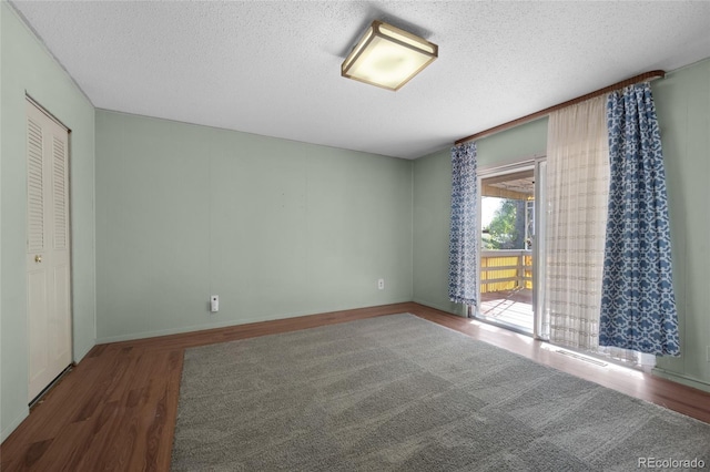 unfurnished bedroom featuring dark hardwood / wood-style floors, a textured ceiling, and a closet