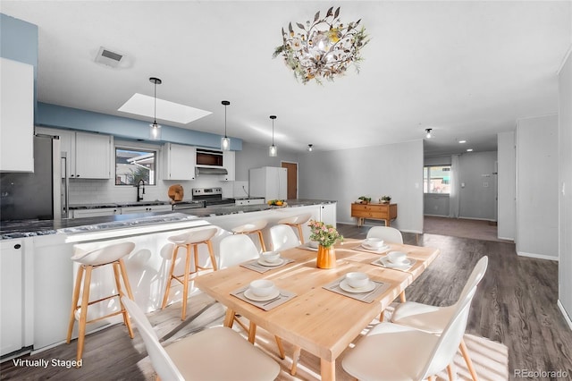 dining space with hardwood / wood-style floors, sink, and a skylight