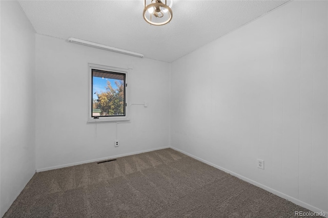 spare room featuring carpet, visible vents, and a textured ceiling