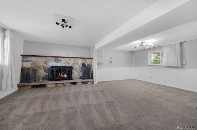 unfurnished living room featuring carpet flooring, a stone fireplace, and a textured ceiling
