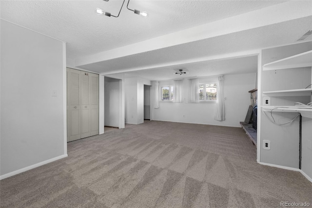 interior space featuring carpet floors, visible vents, a textured ceiling, and baseboards