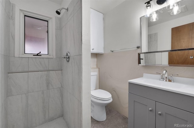full bath featuring tiled shower, vanity, and toilet