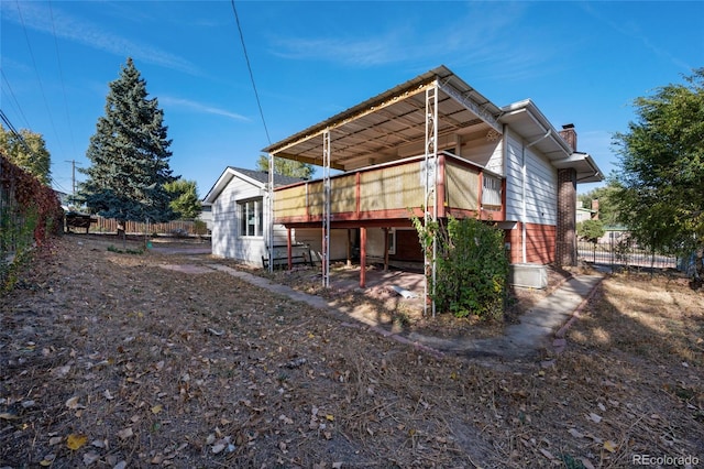 rear view of property with a chimney, fence, and brick siding