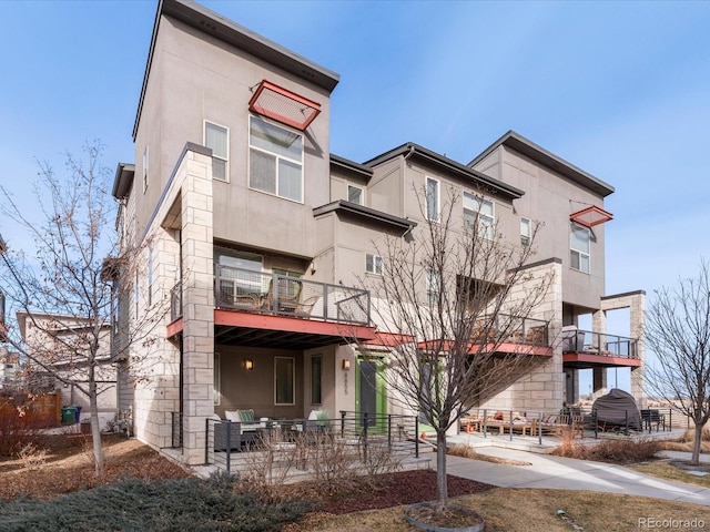 exterior space with stone siding, stucco siding, and a patio