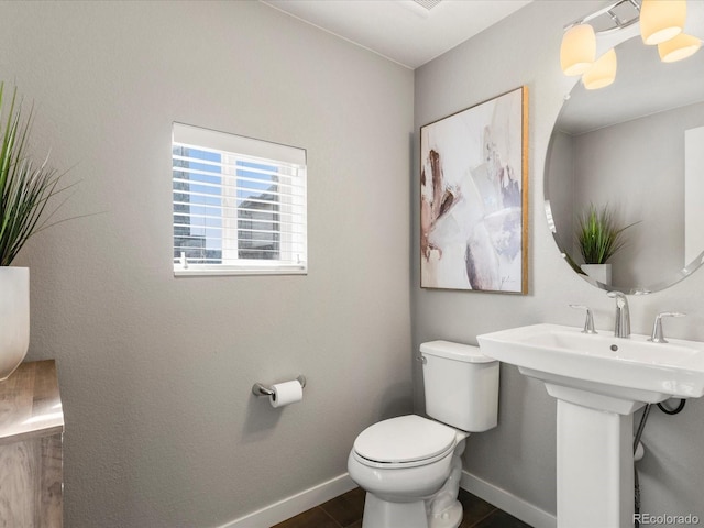 half bathroom featuring toilet, baseboards, and a sink