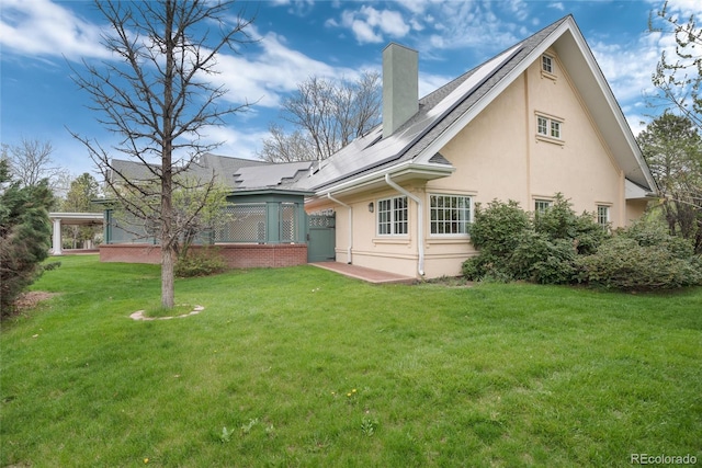 rear view of house featuring brick siding, a patio, a chimney, stucco siding, and a lawn