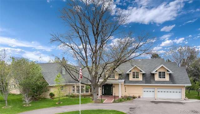 view of front of home featuring aphalt driveway, roof with shingles, a front lawn, and stucco siding