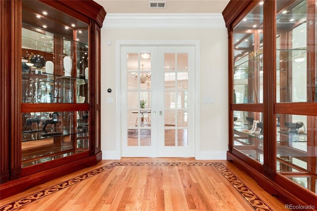 doorway with french doors, crown molding, and wood finished floors