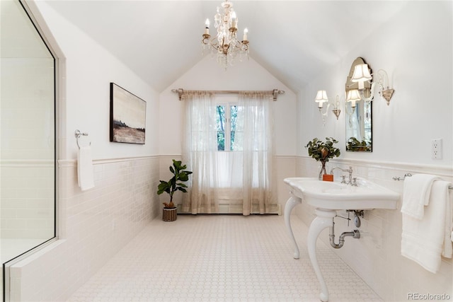 bathroom featuring a notable chandelier, tile walls, lofted ceiling, wainscoting, and tile patterned flooring