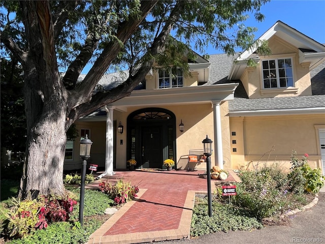 view of front facade featuring a shingled roof and stucco siding