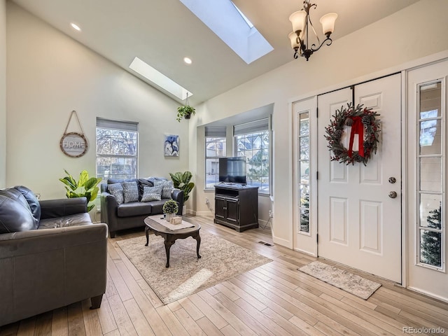 foyer entrance featuring high vaulted ceiling, light wood-type flooring, and a notable chandelier